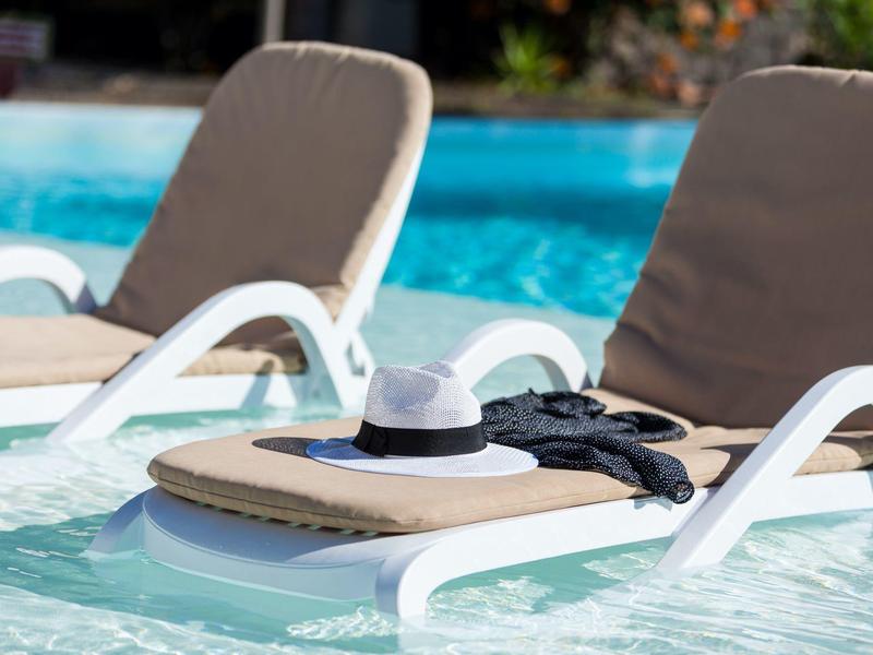 Deux chaises longues dans la piscine avec un chapeau et une robe noire dessus