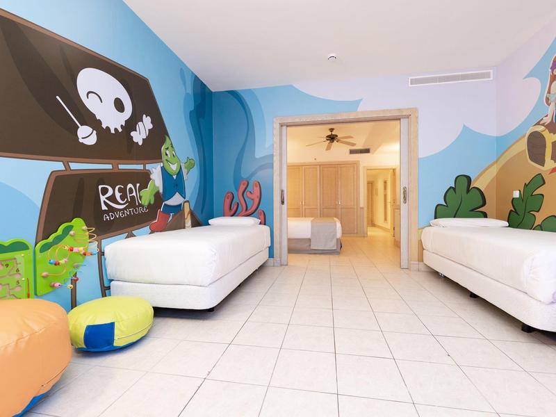 Chambre d'enfant avec motifs de pirates, deux lits simples et coussins colorés.