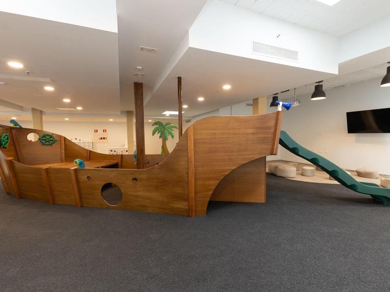 Espace de jeu intérieur avec un bateau pirate en bois et un toboggan.