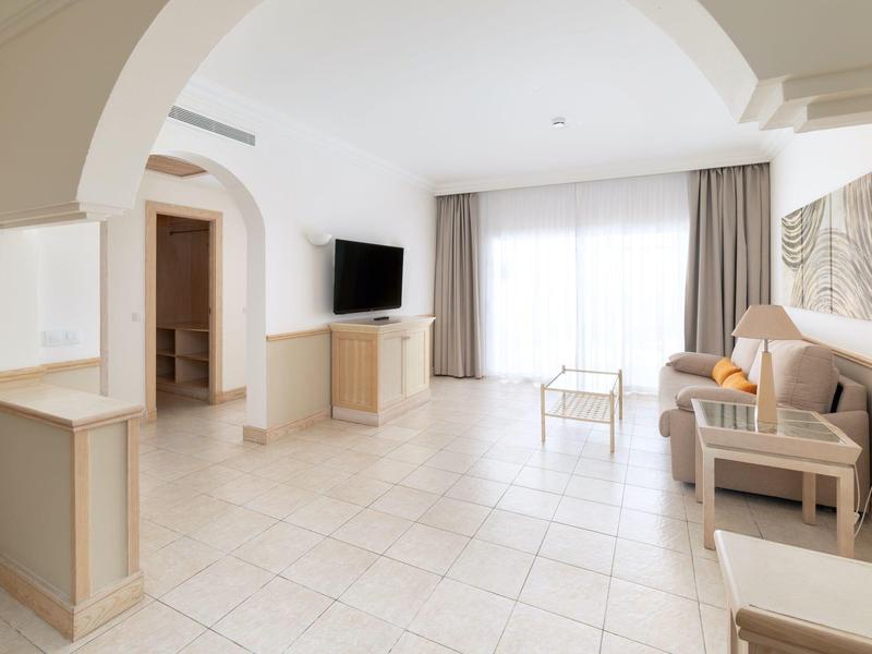 Salon moderne et lumineux avec canapé, télévision et grande fenêtre avec rideaux.