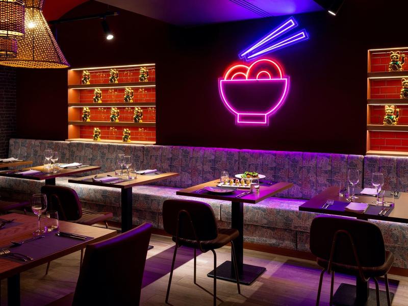 Restaurant moderne avec décoration en néon d'un bol avec des baguettes sur le mur.