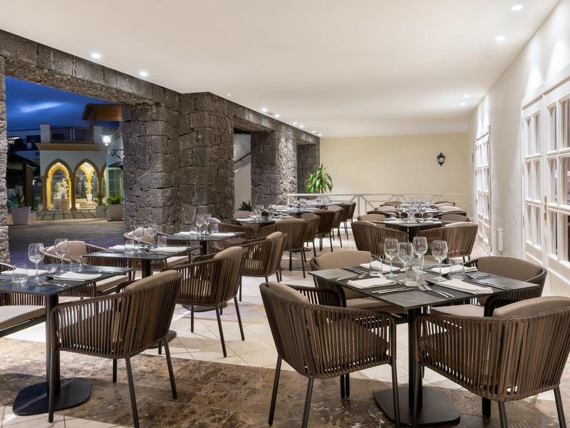 Salle à manger moderne avec tables dressées et chaises confortables dans un espace ouvert.