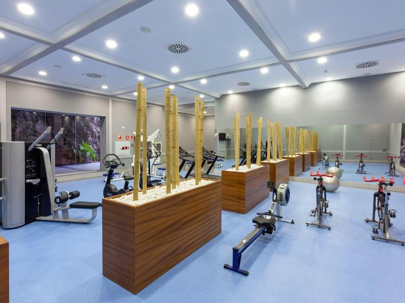 Salle de sport moderne avec équipements et éléments en bois dans une pièce lumineuse.