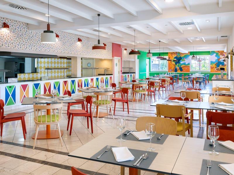 Restaurant coloré et lumineux avec différentes chaises et tables disposées de manière moderne.