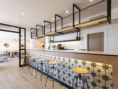 Espace de bar d'hôtel moderne avec carreaux à motifs et tabourets hauts en bois chaleureux.
