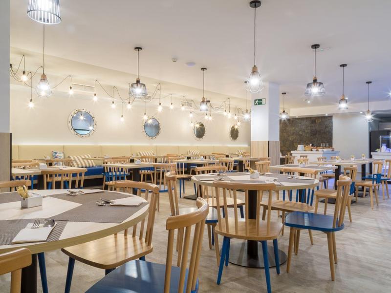 Sala da pranzo moderna e luminosa con sedie in legno e lampade in metallo sul soffitto.