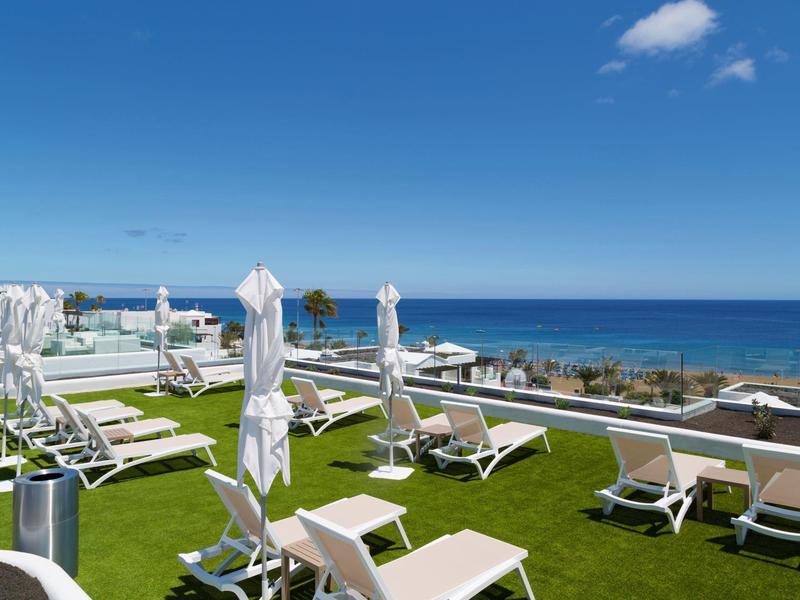 Lettini vuoti su un prato con vista sul mare blu e il cielo.