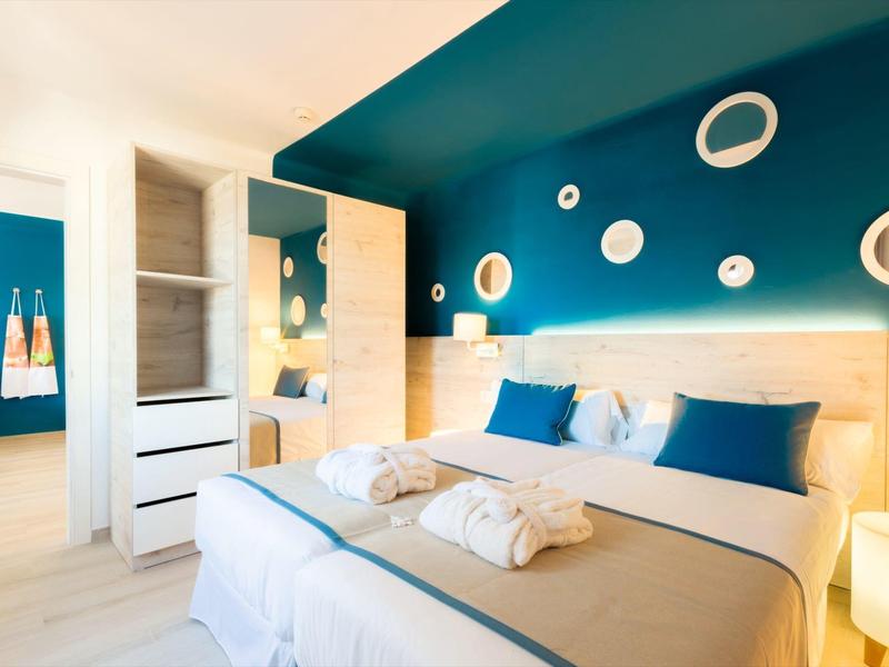 Camera d'hotel luminosa con colori blu e bianco e letto matrimoniale accogliente.