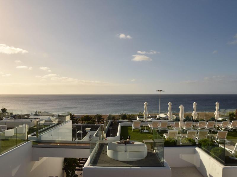 Vista sul mare, lettini e terrazze al tramonto in un hotel.