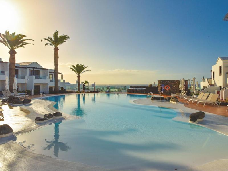 Grande piscina dell'hotel con palme sotto un cielo limpido nel tardo pomeriggio.