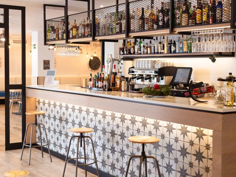 Bar dell'hotel moderno con bancone decorato e sgabelli sotto luce calda.