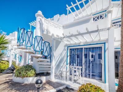 Edificio de hotel blanco de estilo griego con detalles azules bajo un cielo despejado.