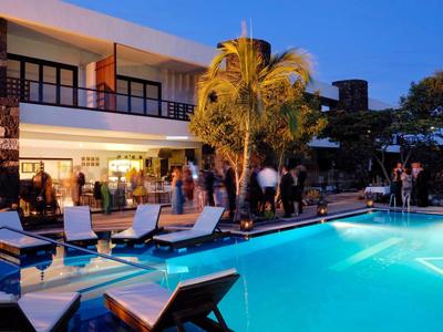 Nowoczesny basen hotelowy o zmierzchu z leżakami i gośćmi w tle