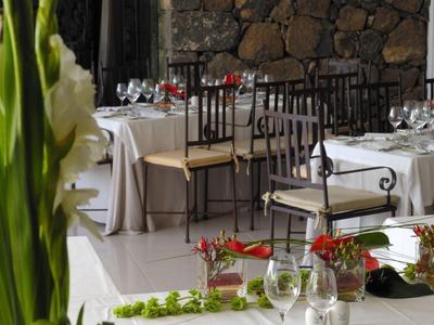 Elegancka jadalnia z nakrytymi stołami i kamienną ścianą w tle.