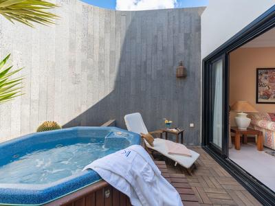 Taras z jacuzzi, leżakiem i widokiem na pokój hotelowy.