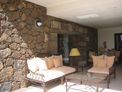 Przytulny kącik wypoczynkowy z tapicerowanymi meblami i lampą przy kamiennej ścianie w hotelu.