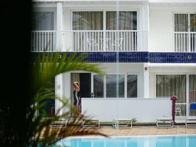 Vista di un hotel con piscina in primo piano e una persona all'ingresso.