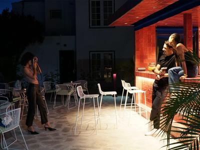 Terrazza del bar serale con ospiti e sedie vuote sotto una luce soffusa.