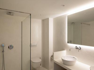 Bagno moderno con doccia, WC, lavabo e grande specchio in tonalità neutre.