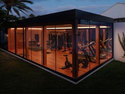 Gimnasio moderno con paredes de vidrio y equipo de ejercicio durante la noche