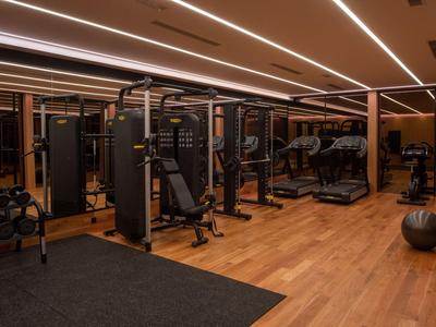 Gimnasio moderno con pesas, equipo de entrenamiento y suelo de madera en un hotel.