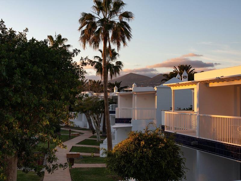 Bungalow vacanze moderni con palme e vista sulle montagne al tramonto.
