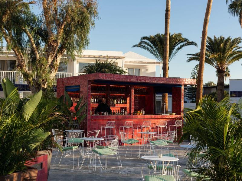 Bar rossa con tavoli e sedie bianchi in giardino tropicale