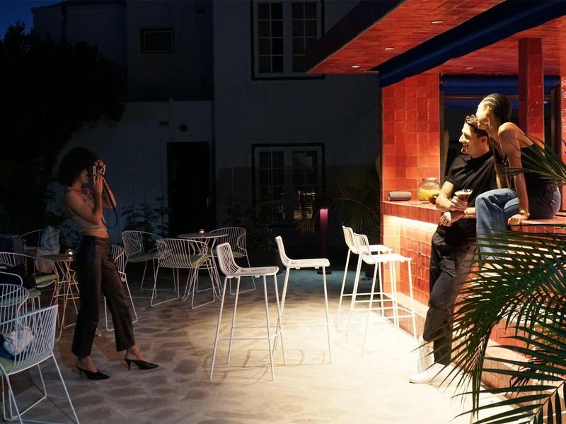 Terrazza del bar serale con ospiti e sedie vuote sotto una luce soffusa.