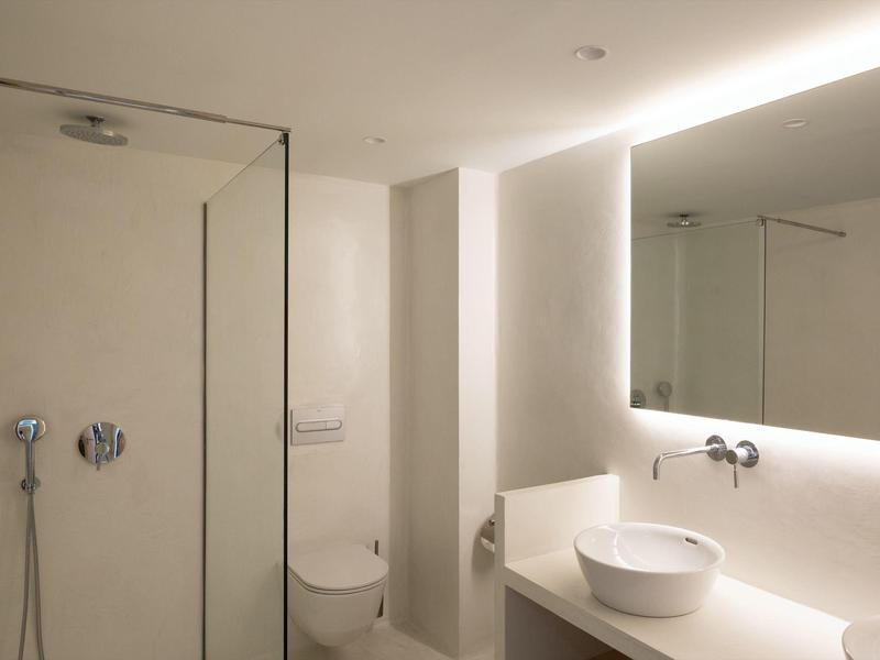 Bagno moderno con doccia, WC, lavabo e grande specchio in tonalità neutre.