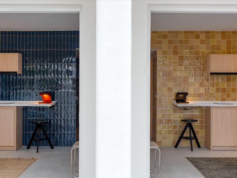 Area pranzo moderna con mobili in legno e pareti piastrellate colorate in una camera d'hotel.