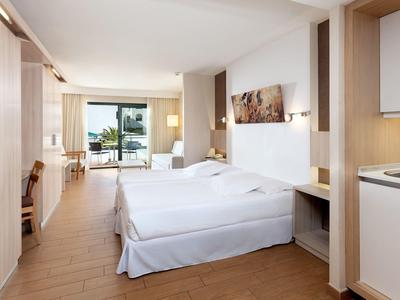 Helles Hotelzimmer mit zwei Einzelbetten, kleinem Balkon und moderner Einrichtung in Holz und Weiß.