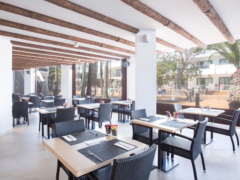 Ampia terrazza coperta dell'hotel con tavoli moderni, sedie e soffitto con travi in legno.