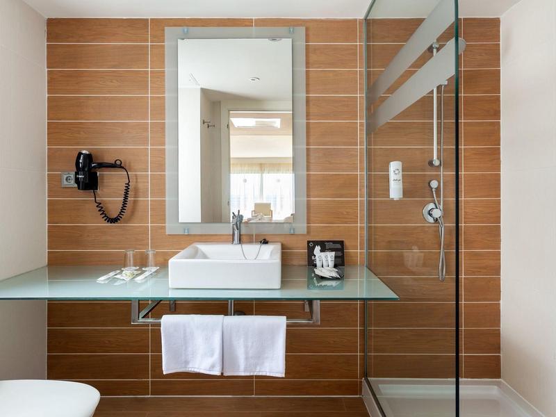 Bagno moderno con lavabo, specchio e piastrelle di legno marrone sulla parete.