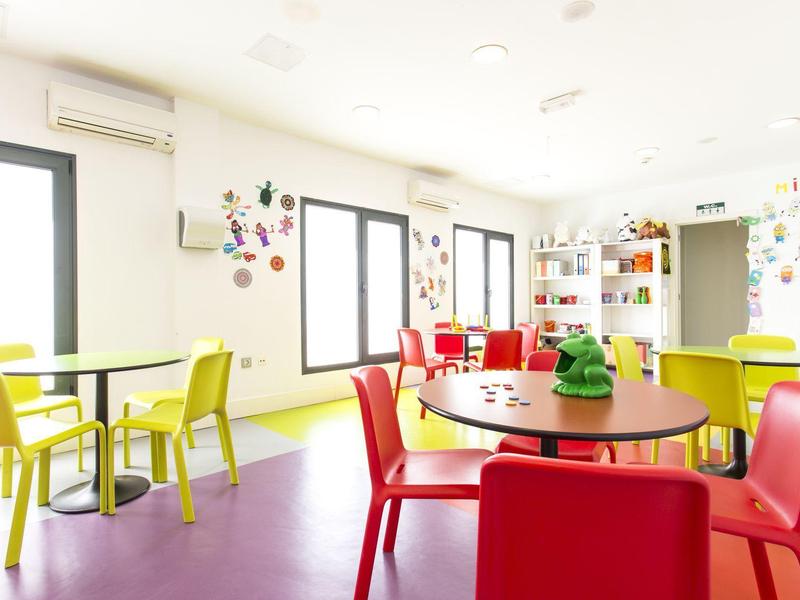 Sala colazioni luminosa e colorata con sedie rosse e gialle e grandi finestre.