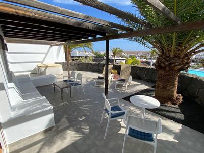 Słoneczny taras z miejscami do siedzenia i palmami, idealny na relaksujące wakacje.