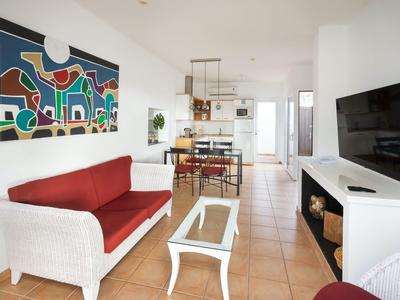 Jasny pokój hotelowy z czerwonym sofą, nowoczesnym stołem i abstrakcyjną sztuką na ścianie.