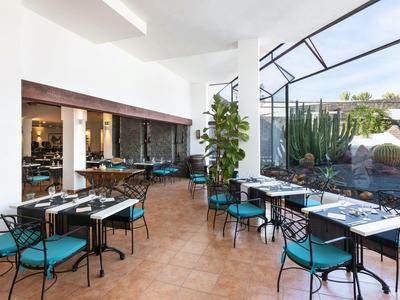 Nowoczesna oranżeria z stołami i krzesłami obok ogrodu z kaktusami.