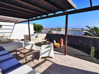 Taras z wygodnymi krzesłami, leżakami i widokiem na morze przy czystym niebie.