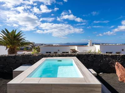 Mały basen z czystą wodą przed białym murem i niebieskim niebem.