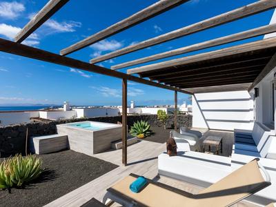 Terrazza con lettini, divano e vista sul mare sotto un cielo azzurro.