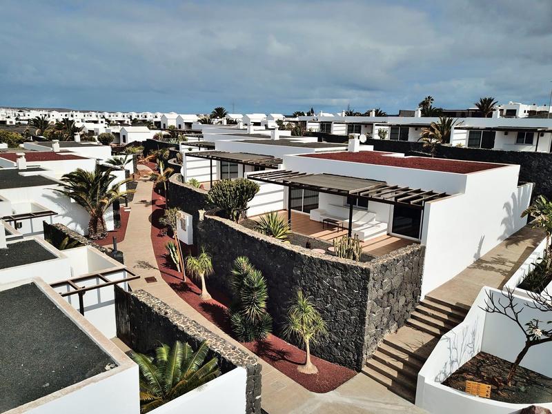 Nowoczesne białe domki wakacyjne z tarasami i ogrodami w słonecznym kurorcie.