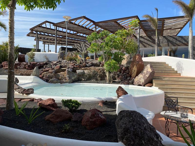 Nowoczesny zewnętrzny basen z wodospadem i naturalnymi kamieniami w hotelu pod czystym niebem.