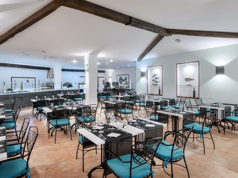 Nowoczesna, jasna jadalnia z niebieskimi krzesłami i czarnymi stołami w hotelu.