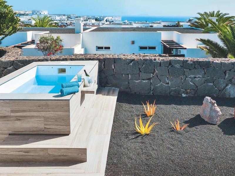 Taras z basenem, miejscem do siedzenia i widokiem na morze w hotelu