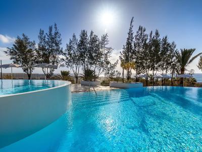 Clear blue pool landscape with trees and bright sunlight in the background.