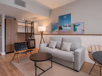 Modern furnished room with gray sofa, round tables, and beach pictures on the wall.