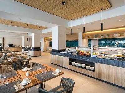 Bright, modern hotel restaurant with set tables and buffet area.