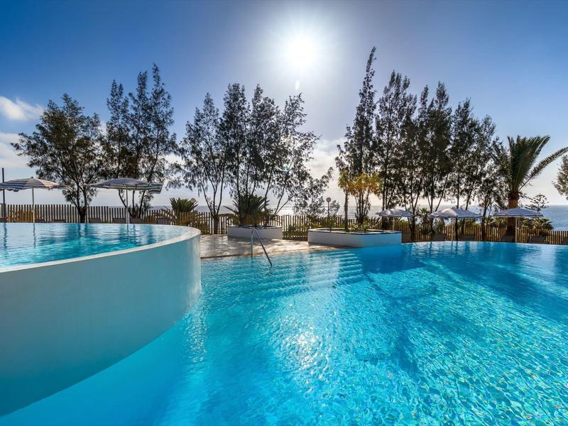 Clear blue pool landscape with trees and bright sunlight in the background.