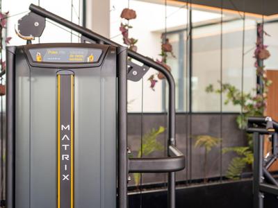 Moderne fitnessapparatuur in een lichte, met planten gevulde hotelruimte.