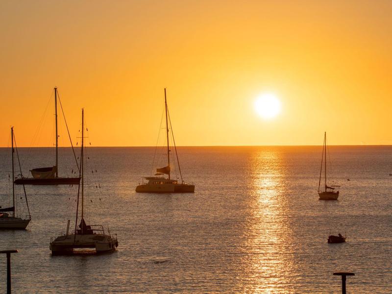 Żaglówki na spokojnym morzu o zachodzie słońca z pomarańczowym niebem